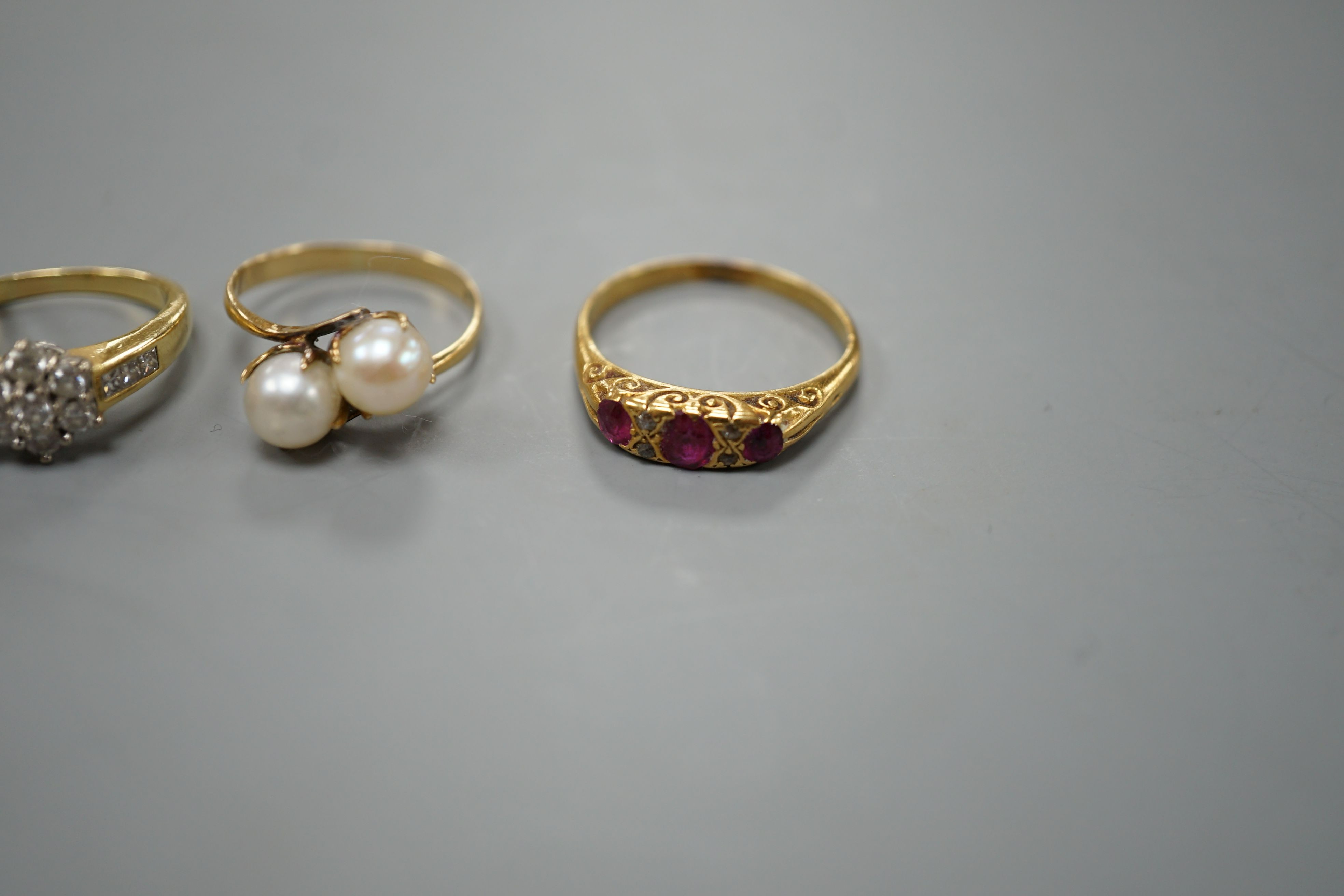 Five assorted gold and gold coloured metal dress rings, comprising a two stone cultured pearl stamped 18k, size L, an 18ct gold diamond cluster, size L, an unmarked citrine?, an 18ct orange stone, size L and an early 20t